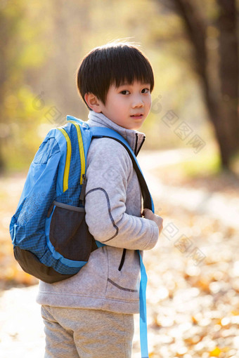 秋天户外小路上背书包的小男孩