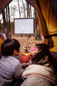 户外露营的儿童趴在帐篷里看电影