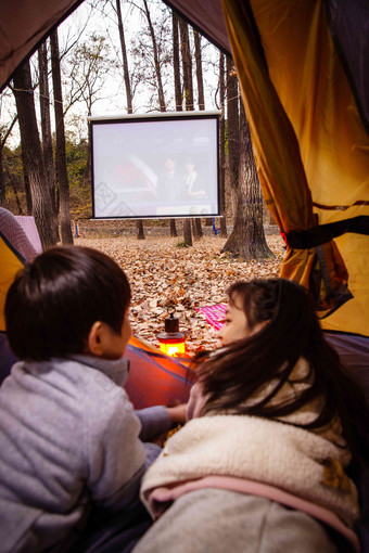 户外露营的儿童趴在帐篷里看电影
