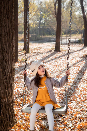 秋天可爱的女孩在户外荡秋千公园清晰场景