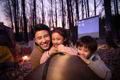 幸福的父亲和两个孩子夜晚野外露营度假高清照片
