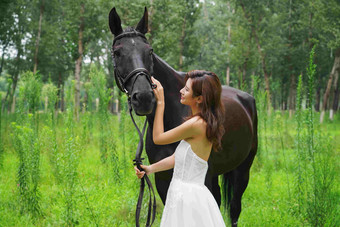 草地上漂亮的青年女人和马