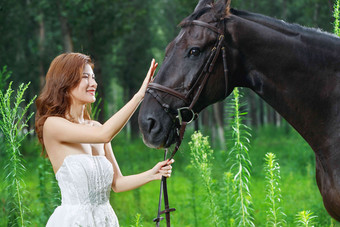 草地上漂亮的青年女人牵着马