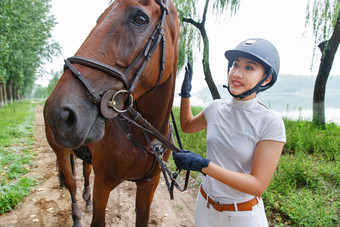 林间小路上女骑手查看马匹状态