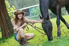户外快乐的青年女人牵着马儿吃草