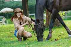 户外青年女人牵着马儿吃草