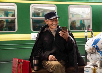 在火车站台上用手机的老人休闲装高质量素材