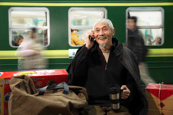 在火车站台上打电话的老人杯子高端照片