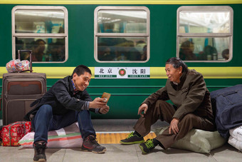 两名男子在火车月台上看<strong>手机</strong>