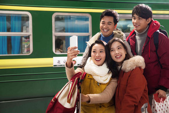 青年男女在火车站台上用手机爱影相