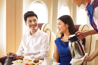 年轻夫妇在飞机上用餐关爱高清相片