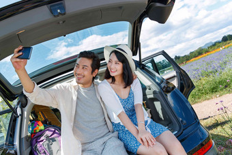 青年夫妇坐在汽车后备箱里拍照青年伴侣高质量拍摄