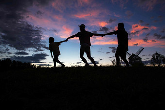 夕阳下幸福的<strong>一家</strong>三<strong>口</strong>手牵手自然摄影图