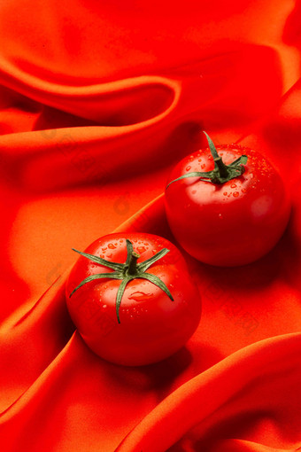 红色丝绸上摆放西红柿维生素高清拍摄