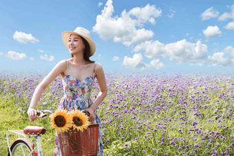 在花海里骑自行车的青年女人摄影高清相片