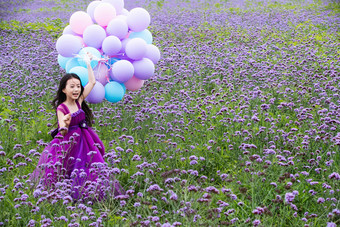 拿着气球的小女孩在花海里奔跑