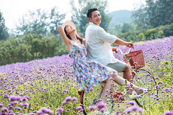 青年夫妇在花海里骑车紫色高端图片