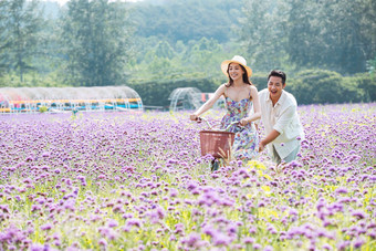 青年夫妇在花海里<strong>骑车</strong>不看镜头写实拍摄