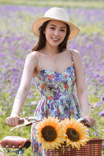 青年女人在花海里骑自行车白昼写实照片