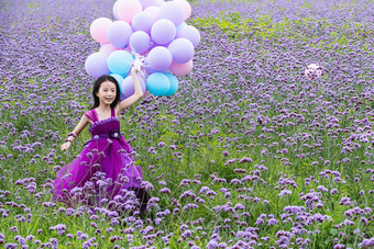 拿着气球的小女孩在花海里奔跑中国拍摄