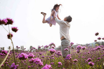 父亲抱着女儿在花丛中<strong>玩耍</strong>