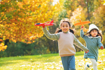 拿着玩具飞机在公园玩耍的女孩