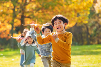 快乐儿童拿着玩具飞机在公园玩耍
