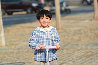 快乐的男孩在户外玩<strong>滑板车</strong>