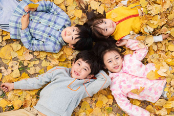 可爱的小朋友们躺在落叶上玩耍四个人高清拍摄