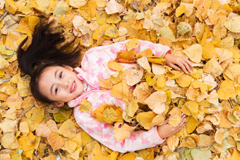 <strong>快乐</strong>的小女孩躺在落叶上玩耍<strong>成长</strong>写实照片