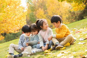 四个小朋友坐在草地上看平板电脑水平构图高端图片