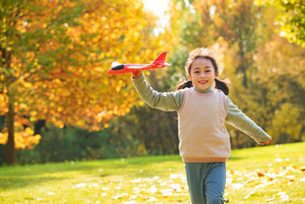 拿着玩具飞机在公园玩耍的快乐女孩
