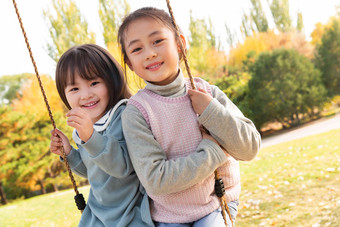 两个女孩在公园里荡秋千摄影氛围图片