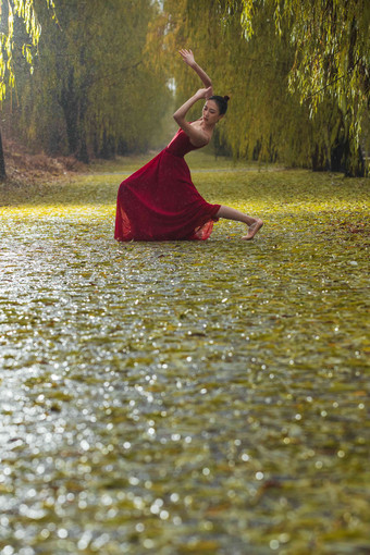 穿红色裙子的青年女人在户外跳芭蕾舞