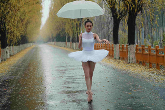 拿着雨伞的青年女人跳芭蕾舞