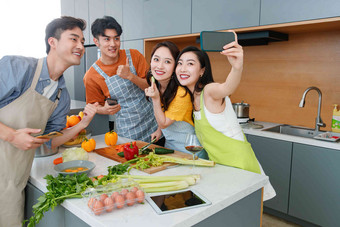 年轻朋友在厨房做饭照相微笑高端图片