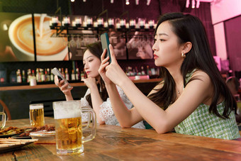 在酒吧里玩手机的青年女人