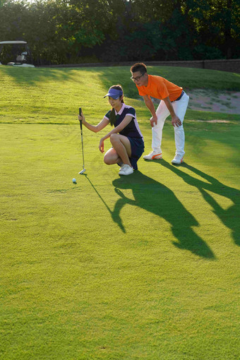 球场上教练指导青年女人打高尔夫自然地理清晰场景