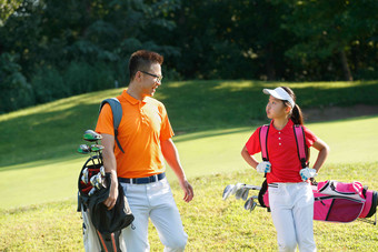 球场上教练和学生背着高尔夫球包交谈锻炼高清场景