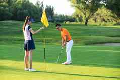 高尔夫球场上教练给青年女人做示范