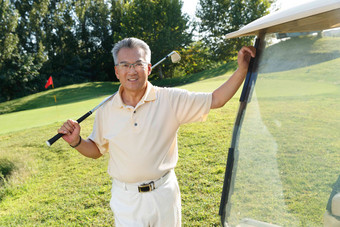 快乐的老年人扛着球杆站在高尔夫球车旁
