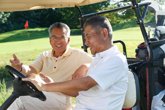 中年男人和老年人坐在高尔夫球车上交谈合作写实摄影图