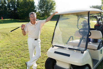 快乐的老年人扛着球杆站在高尔夫球车旁享乐清晰摄影图