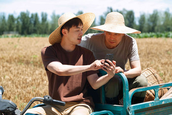 农民坐在三轮车上使用手机互联网清晰摄影图