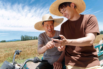 农民坐在三轮车上使用手机小麦清晰图片