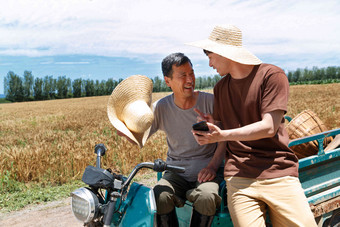 农民坐在三轮车上使用手机