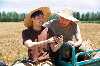 农民坐在三轮车上使用手机交流高端素材