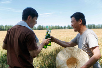 农民在麦田旁喝啤酒丰收场景