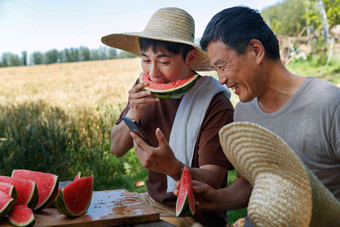 农民在田地旁休息吃西瓜拿着照片