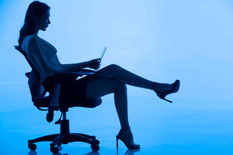 商务女士坐在椅子上使用电脑逆光高质量相片